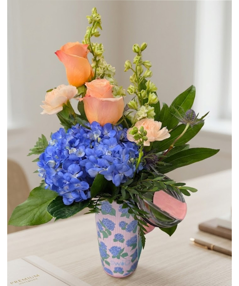 Features peach roses and blue hydrangea arranged inside a reusable Swig Hydrangea travel tumbler