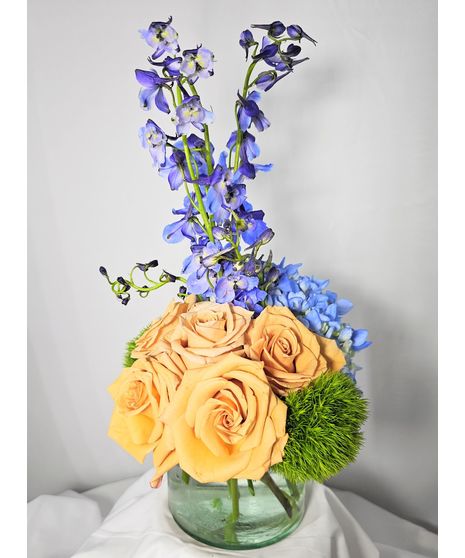 Toffee roses, blue delphinium, blue hydrangea and green tricks in a cylinder vase