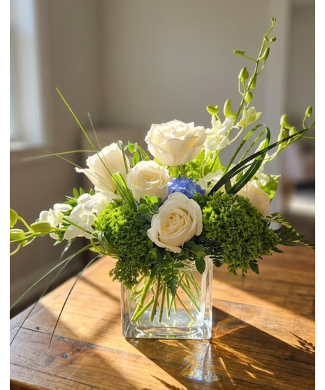 this bouquet features premium white roses, delicate orchids, and a bold sapphire-blue hydrangea in a modern glass cube vase.