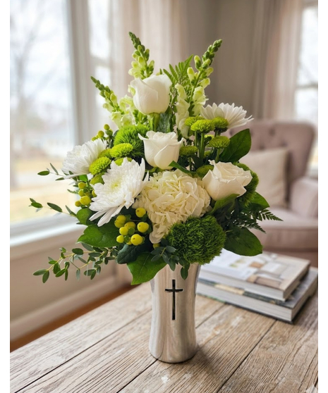 white roses, hydrangea, and vibrant greens in a cross-embellished silver vase.